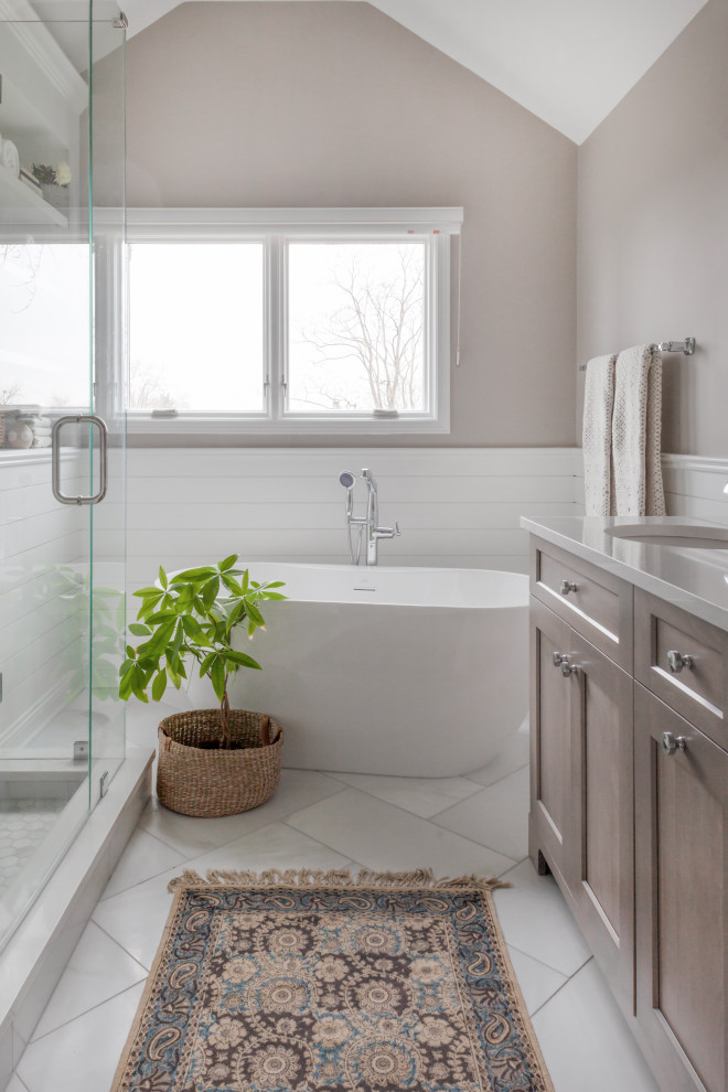 Пример оригинального дизайна: главная ванная комната среднего размера в стиле неоклассика (современная классика) с фасадами в стиле шейкер, серыми фасадами, отдельно стоящей ванной, угловым душем, раздельным унитазом, белой плиткой, мраморной плиткой, серыми стенами, мраморным полом, накладной раковиной, столешницей из искусственного кварца, белым полом, душем с распашными дверями, белой столешницей, сиденьем для душа, тумбой под две раковины, напольной тумбой, сводчатым потолком и стенами из вагонки
