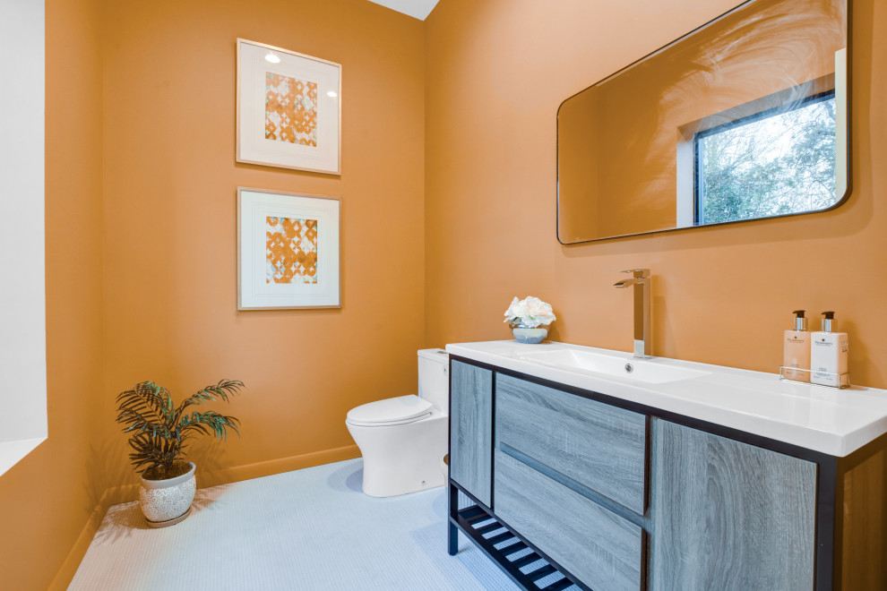 ニューヨークにある中くらいなコンテンポラリースタイルのおしゃれなバスルーム (浴槽なし) (フラットパネル扉のキャビネット、中間色木目調キャビネット、一体型トイレ	、オレンジの壁、一体型シンク、グレーの床、白い洗面カウンター) の写真