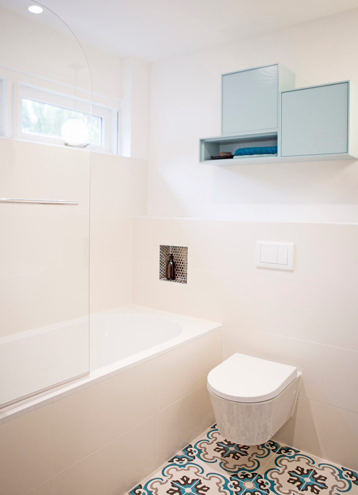 На фото: главная ванная комната среднего размера в средиземноморском стиле с синими фасадами, ванной в нише, душем над ванной, унитазом-моноблоком, белой плиткой, керамической плиткой, белыми стенами, полом из терракотовой плитки и подвесной раковиной