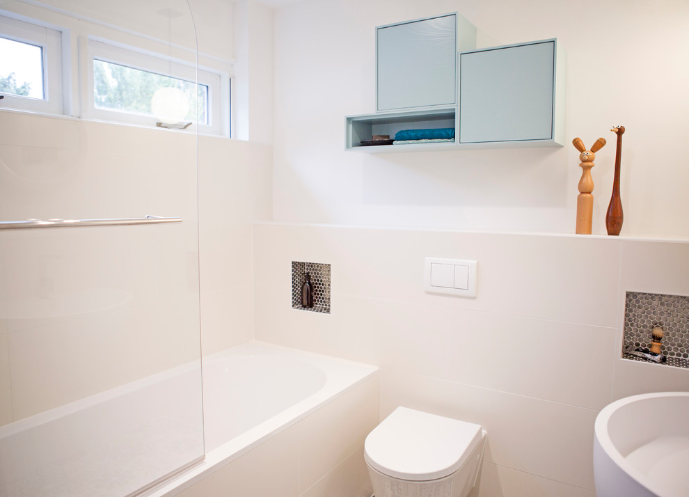 This is an example of a medium sized modern ensuite bathroom in Amsterdam with freestanding cabinets, blue cabinets, an alcove bath, a shower/bath combination, a one-piece toilet, white tiles, ceramic tiles, white walls, terracotta flooring and a wall-mounted sink.