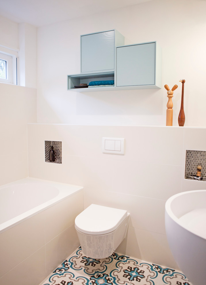 Photo of a medium sized modern ensuite bathroom in Amsterdam with freestanding cabinets, blue cabinets, an alcove bath, a shower/bath combination, a one-piece toilet, white tiles, ceramic tiles, white walls, terracotta flooring and a wall-mounted sink.
