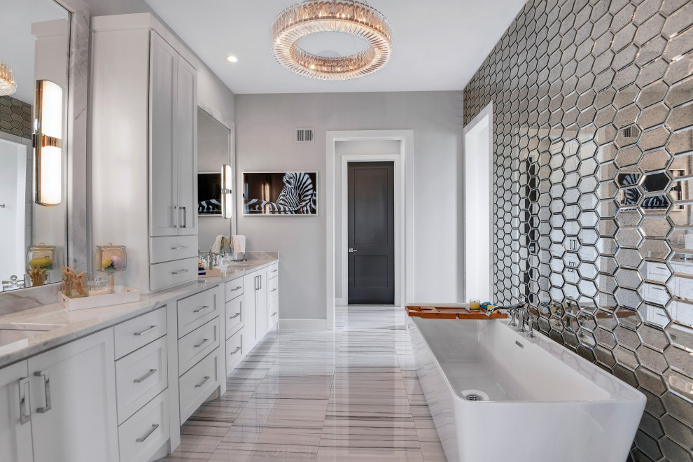 Пример оригинального дизайна: главная ванная комната в стиле неоклассика (современная классика) с фасадами в стиле шейкер, белыми фасадами, отдельно стоящей ванной, зеркальной плиткой, серыми стенами, врезной раковиной, мраморной столешницей и серым полом