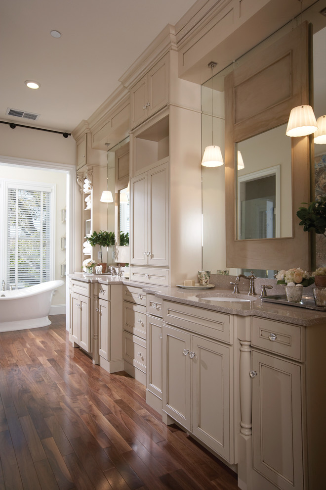 Immagine di una grande stanza da bagno padronale classica con ante a filo, ante beige, vasca freestanding, pareti beige, parquet scuro e lavabo sottopiano