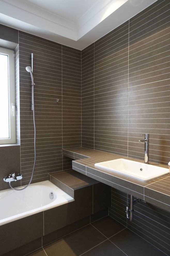 This is an example of a contemporary bathroom with a built-in sink and brown tiles.