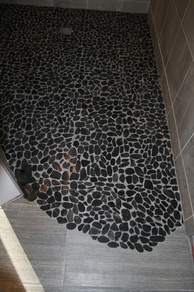 Diseño de cuarto de baño principal moderno grande con ducha a ras de suelo, baldosas y/o azulejos negros y suelo de baldosas tipo guijarro