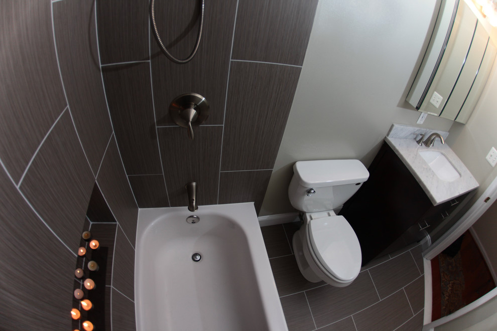 Exemple d'une petite salle de bain principale moderne en bois foncé avec un lavabo encastré, un placard à porte plane, un plan de toilette en marbre, un combiné douche/baignoire, WC séparés, un carrelage gris, des carreaux de porcelaine, un mur blanc et un sol en carrelage de porcelaine.