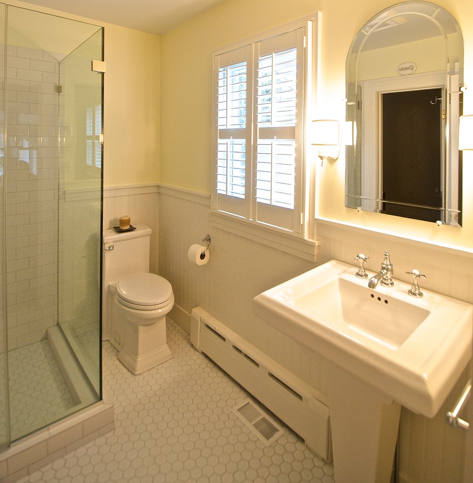 Ispirazione per una stanza da bagno tradizionale di medie dimensioni con lavabo a colonna, doccia ad angolo, WC monopezzo, piastrelle bianche, piastrelle in ceramica, pareti gialle e pavimento con piastrelle in ceramica