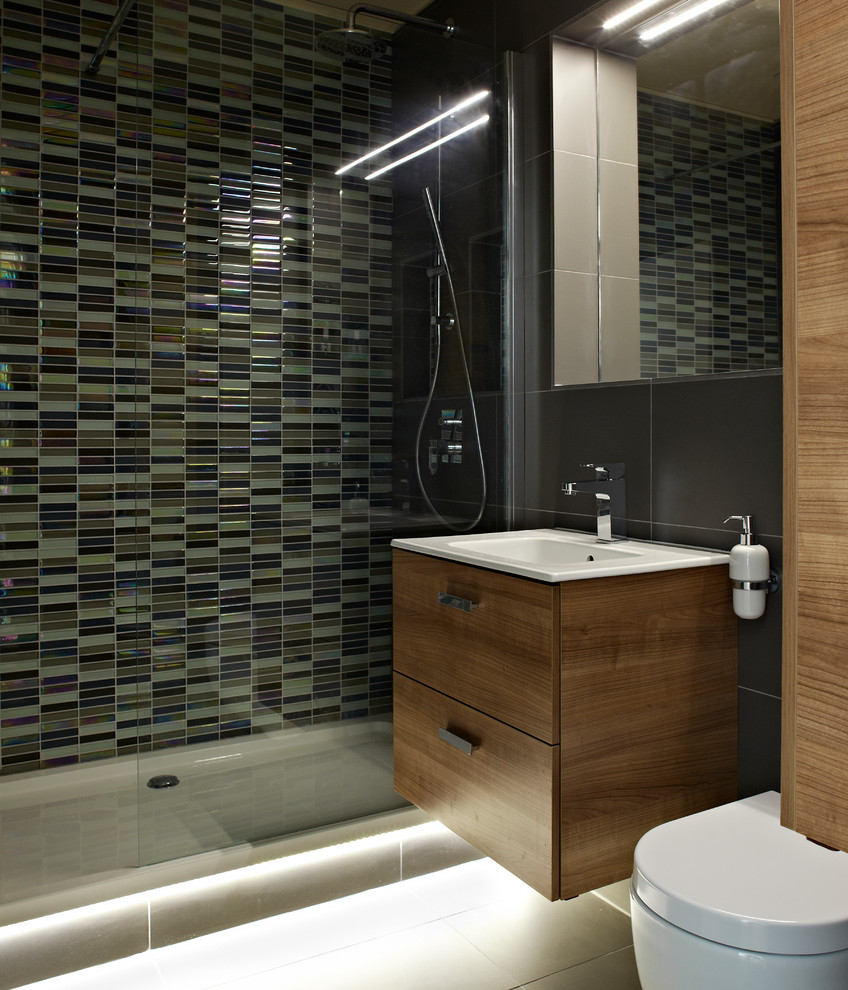 Inspiration for a medium sized contemporary bathroom in London with an integrated sink, freestanding cabinets, dark wood cabinets, a walk-in shower, a wall mounted toilet, grey tiles, ceramic tiles, grey walls and ceramic flooring.