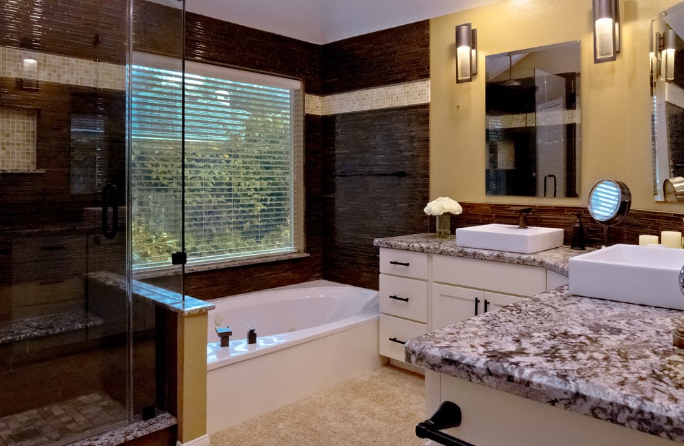 На фото: главная ванная комната среднего размера в стиле неоклассика (современная классика) с фасадами в стиле шейкер, белыми фасадами, угловой ванной, угловым душем, коричневой плиткой, желтыми стенами, настольной раковиной, столешницей из гранита, бежевым полом, душем с распашными дверями, серой столешницей и удлиненной плиткой с