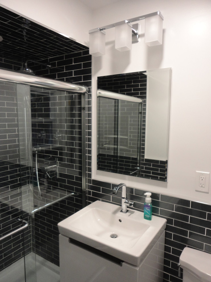 Immagine di una piccola stanza da bagno con doccia minimalista con piastrelle grigie, piastrelle di vetro, pavimento in gres porcellanato, pavimento grigio, porta doccia scorrevole e WC monopezzo