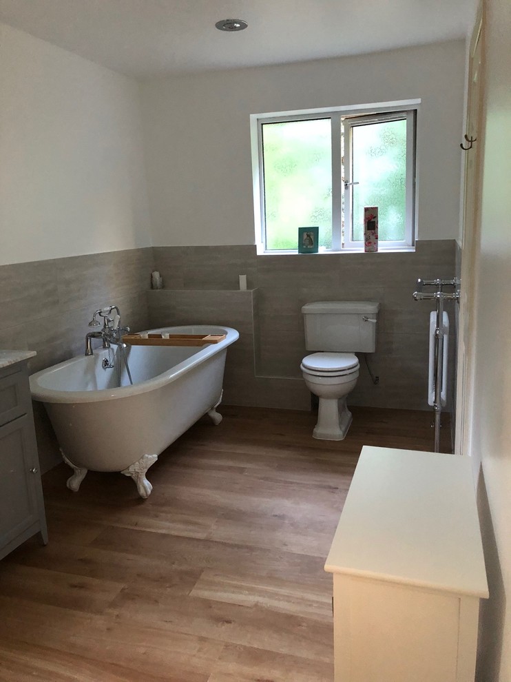 Immagine di una stanza da bagno per bambini moderna di medie dimensioni con consolle stile comò, ante bianche, vasca freestanding, doccia aperta, WC monopezzo, piastrelle beige, piastrelle in terracotta, pareti beige, pavimento in laminato, lavabo da incasso, top in marmo, pavimento marrone, porta doccia a battente e top grigio