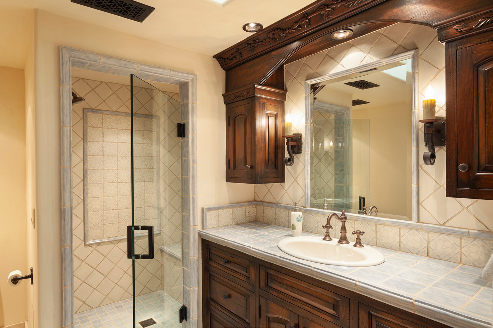 Bild på ett mellanstort lantligt beige beige badrum, med luckor med upphöjd panel, skåp i slitet trä, en dusch i en alkov, blå kakel, keramikplattor, beige väggar, travertin golv, ett nedsänkt handfat, bänkskiva i kalksten, beiget golv och dusch med gångjärnsdörr