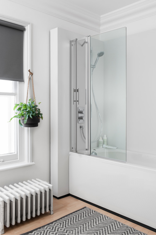 Foto de cuarto de baño nórdico con bañera empotrada, combinación de ducha y bañera, paredes blancas, suelo de madera clara y ducha abierta