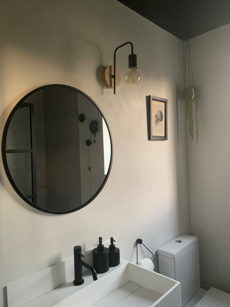 Exempel på ett litet industriellt en-suite badrum, med släta luckor, vita skåp, en öppen dusch, en toalettstol med hel cisternkåpa, grå kakel, porslinskakel, vita väggar, vinylgolv, ett väggmonterat handfat, brunt golv och med dusch som är öppen