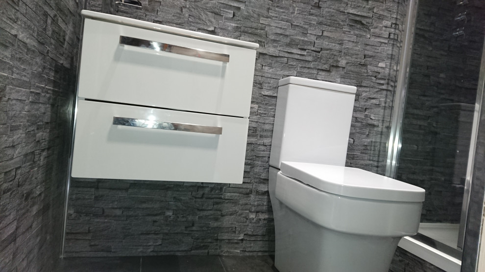 Small modern ensuite bathroom in Other with freestanding cabinets, white cabinets, a built-in shower, a two-piece toilet, grey tiles, slate tiles, grey walls, vinyl flooring, a wall-mounted sink, grey floors and a sliding door.