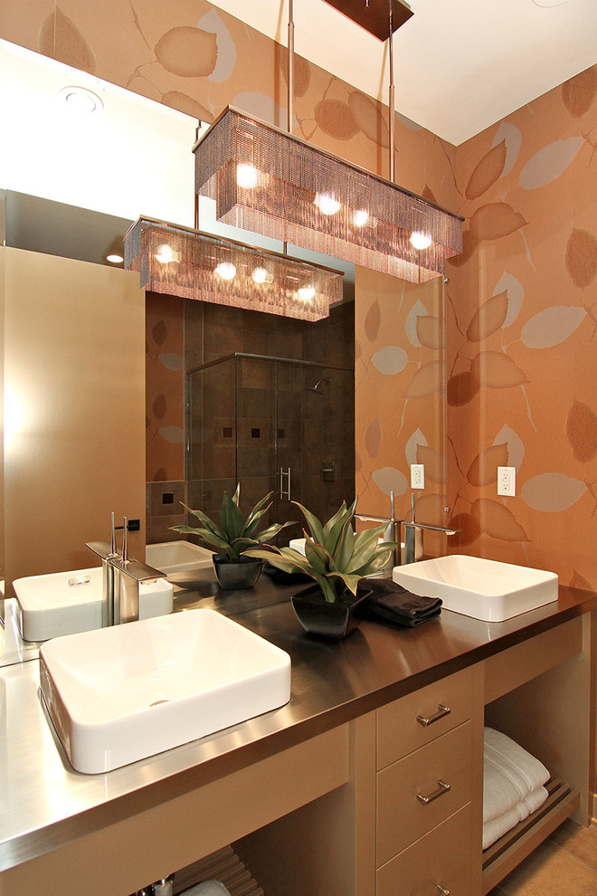 Modern inredning av ett mellanstort en-suite badrum, med ett fristående handfat, släta luckor, bruna skåp, bänkskiva i rostfritt stål, ett undermonterat badkar, en dusch i en alkov och en toalettstol med separat cisternkåpa