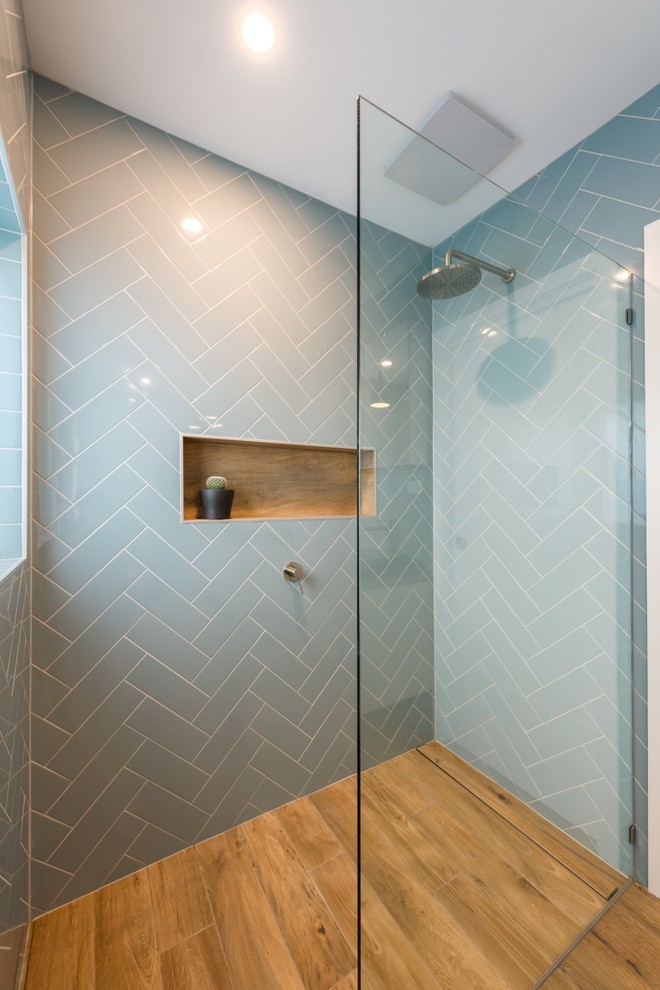 Modelo de cuarto de baño principal con ducha abierta y suelo de madera en tonos medios