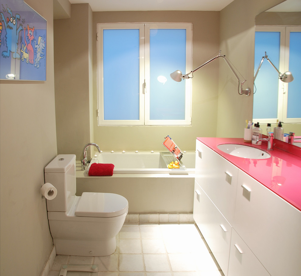 Cette photo montre une salle de bain tendance avec un lavabo encastré, un placard à porte plane, des portes de placard blanches, une baignoire posée, WC séparés et un plan de toilette rose.