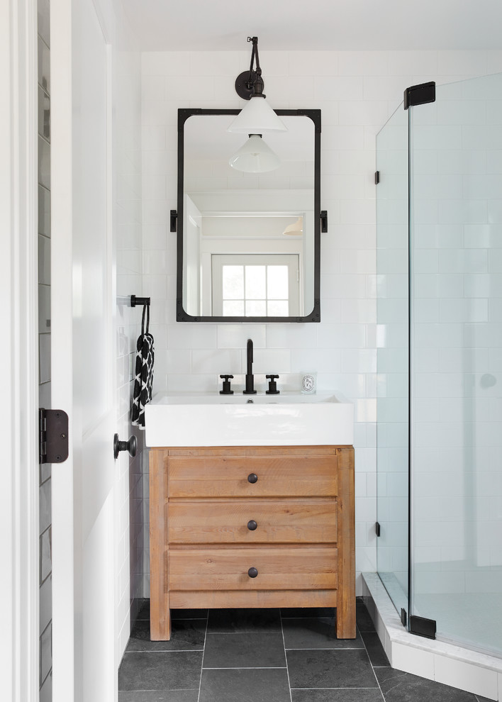 Cette photo montre une petite salle de bain nature en bois brun avec un placard à porte plane, une douche d'angle, un carrelage blanc, des carreaux de céramique, un mur blanc, un plan vasque et une cabine de douche à porte battante.
