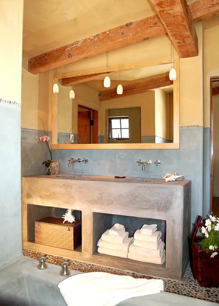 Immagine di una stanza da bagno padronale stile rurale di medie dimensioni con nessun'anta, vasca ad alcova, pareti blu, pavimento con piastrelle di ciottoli, lavabo integrato e top in cemento