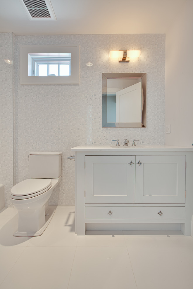 Exemple d'une salle de bain bord de mer de taille moyenne avec un lavabo encastré, un placard avec porte à panneau encastré, des portes de placard blanches, un plan de toilette en marbre, une baignoire en alcôve, un combiné douche/baignoire, WC à poser, un carrelage blanc, mosaïque, un mur blanc, un sol en carrelage de céramique, un sol blanc et une cabine de douche avec un rideau.