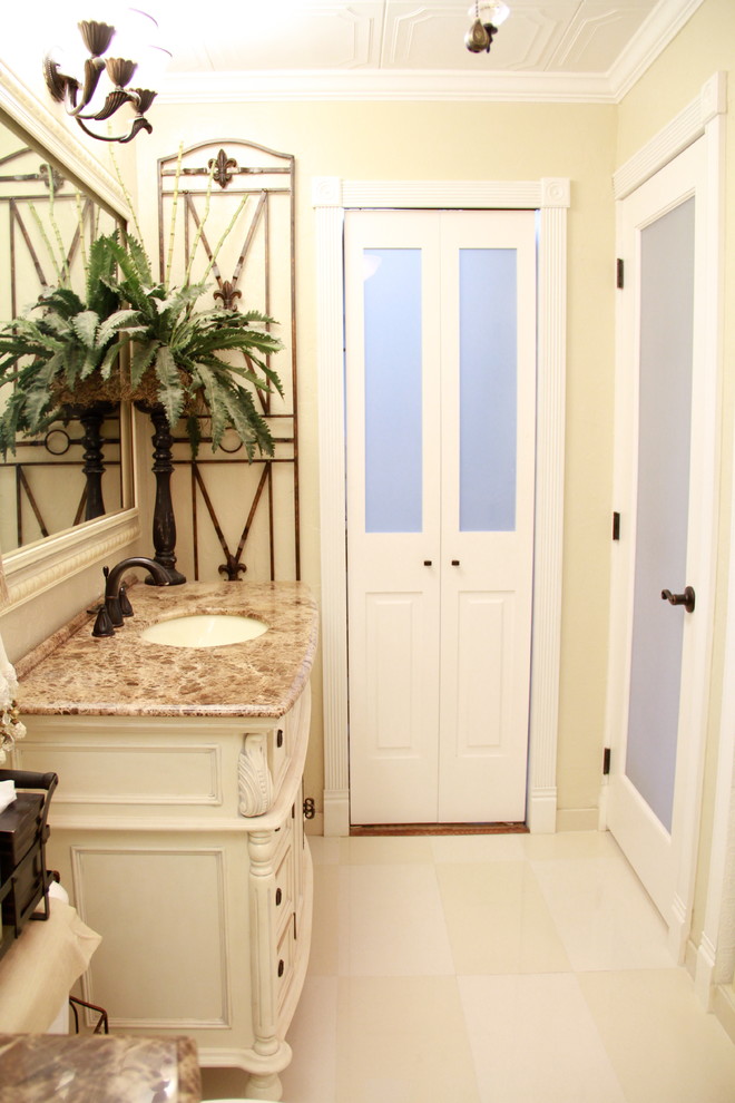 Klassisk inredning av ett mellanstort en-suite badrum, med ett integrerad handfat, möbel-liknande, marmorbänkskiva, en dusch/badkar-kombination, en toalettstol med hel cisternkåpa, vit kakel, beige väggar, marmorgolv och vita skåp
