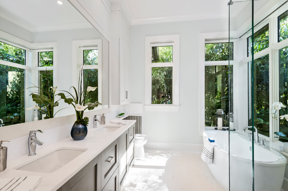 Klassisches Badezimmer mit Schrankfronten im Shaker-Stil, grauen Schränken, freistehender Badewanne, weißer Wandfarbe, Unterbauwaschbecken und beigem Boden in Sonstige