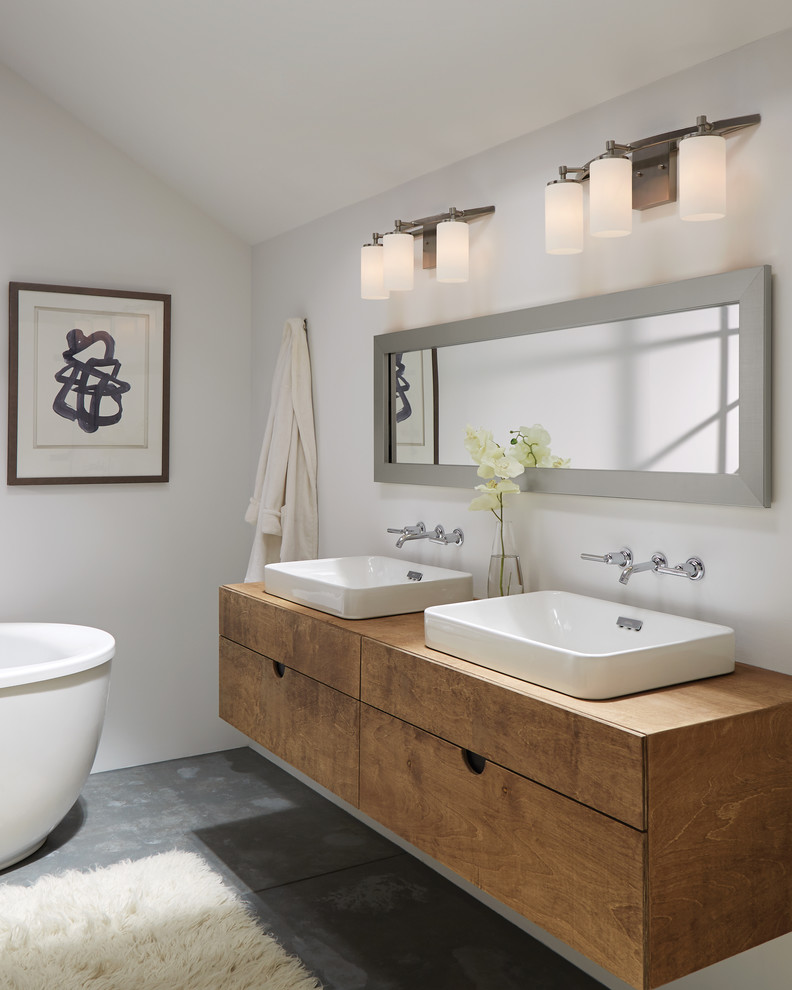 Bild på ett litet funkis brun brunt badrum, med släta luckor, skåp i mellenmörkt trä, ett fristående badkar, vita väggar, betonggolv, ett avlångt handfat och träbänkskiva