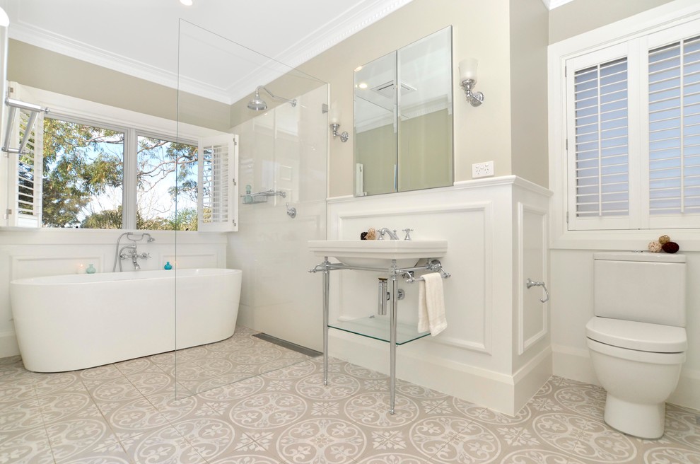 Inredning av ett klassiskt mellanstort badrum, med ett fristående badkar, en öppen dusch, en toalettstol med separat cisternkåpa, beige väggar, ett konsol handfat och med dusch som är öppen