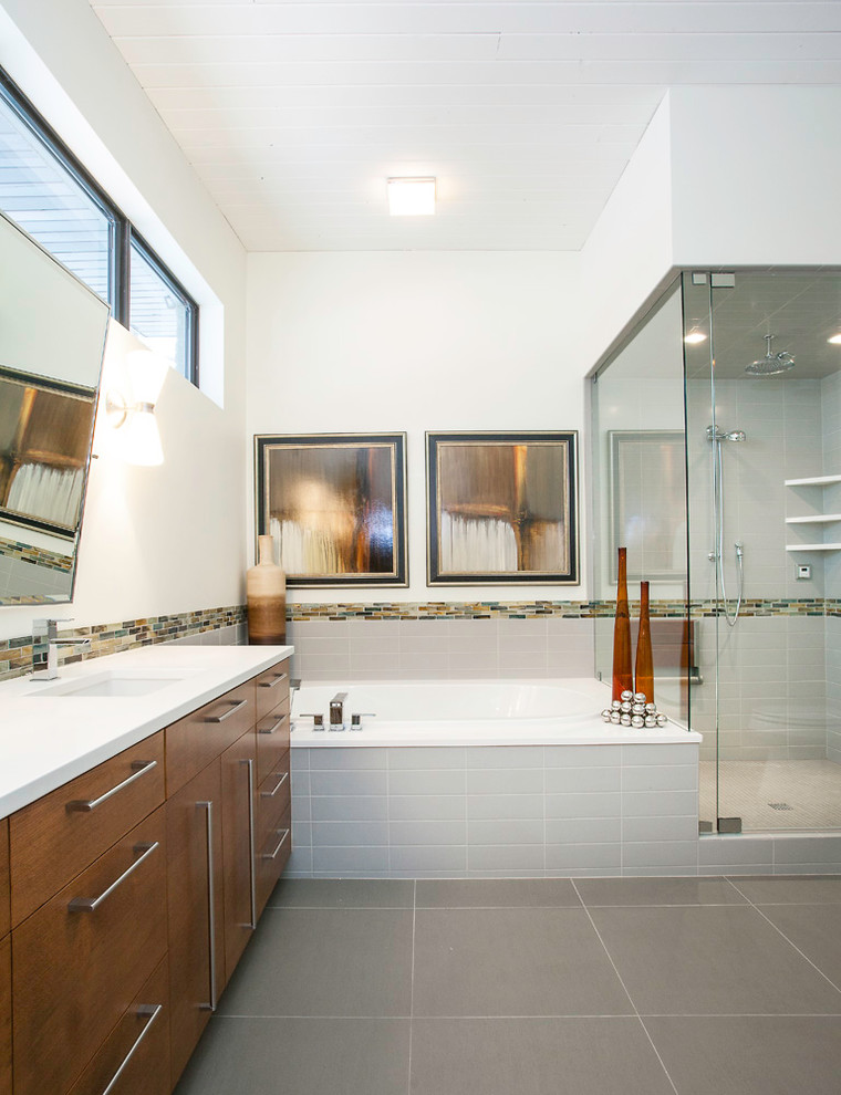 Cette image montre une salle de bain principale vintage en bois brun de taille moyenne avec un placard à porte plane, une baignoire posée, une douche d'angle, un carrelage gris, un carrelage orange, un carrelage blanc, un carrelage jaune, un mur blanc, un lavabo encastré, un carrelage en pâte de verre, un sol en carrelage de porcelaine, un plan de toilette en quartz, un sol gris et une cabine de douche à porte battante.