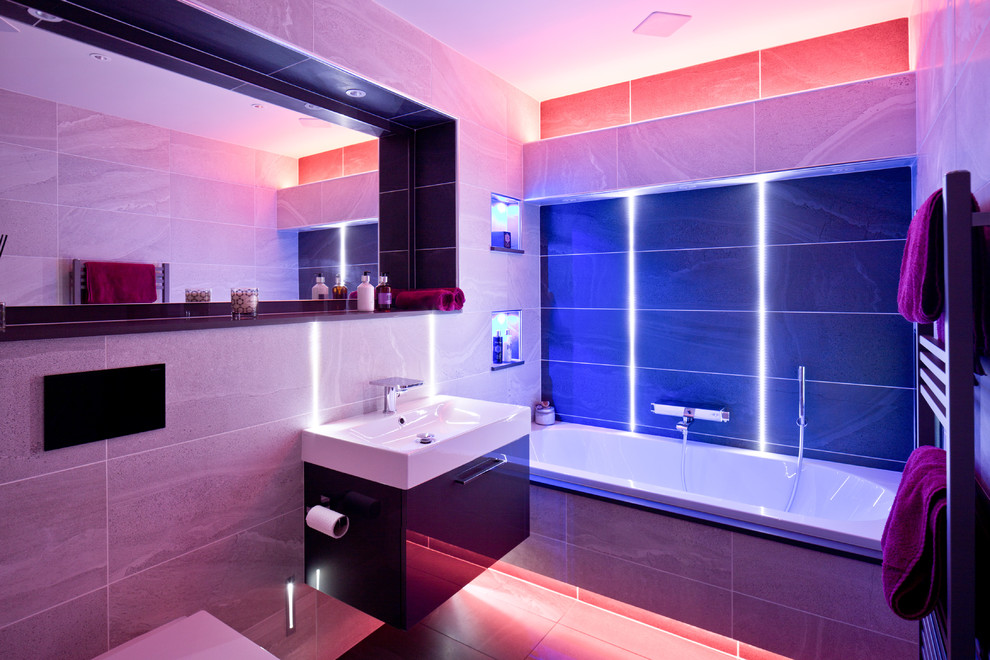 他の地域にある高級な小さなコンテンポラリースタイルのおしゃれな浴室 (一体型シンク、フラットパネル扉のキャビネット、濃色木目調キャビネット、ドロップイン型浴槽、照明) の写真