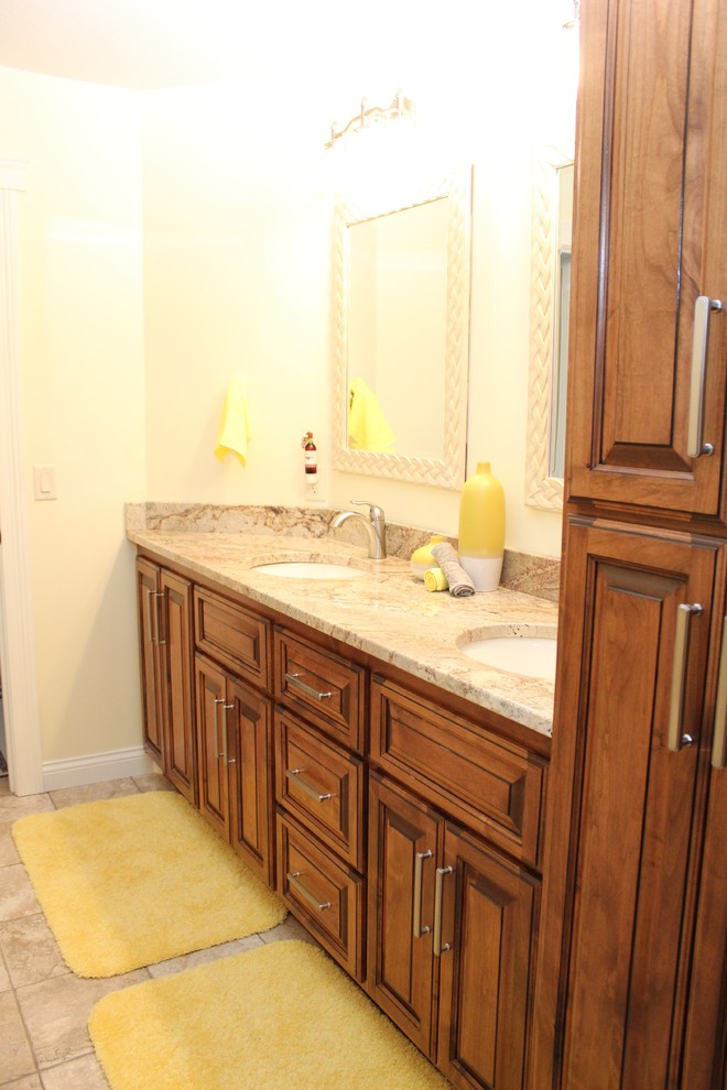 Idées déco pour une grande salle de bain principale classique en bois brun avec un lavabo posé, un placard avec porte à panneau surélevé, un plan de toilette en granite, un carrelage beige, un mur beige et un sol en carrelage de céramique.