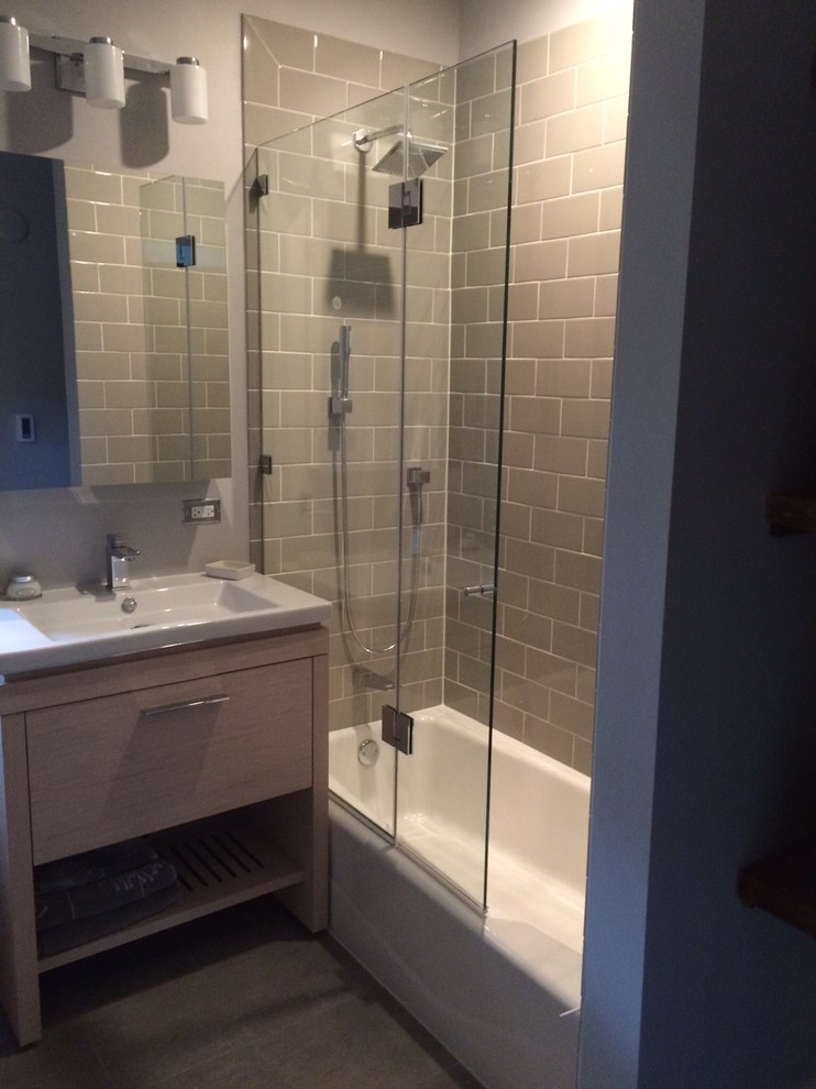 На фото: большая главная ванная комната в современном стиле с плоскими фасадами, коричневыми фасадами, ванной в нише, душем над ванной, серой плиткой, серыми стенами, серым полом и душем с раздвижными дверями с