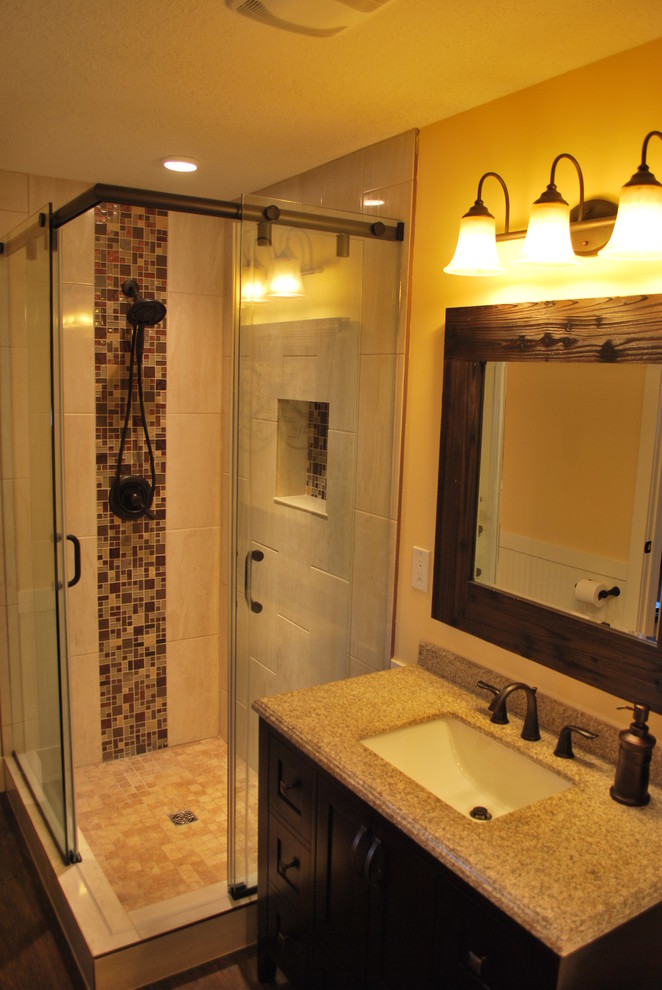 Bild på ett mellanstort rustikt badrum med dusch, med en toalettstol med separat cisternkåpa, flerfärgad kakel, stenkakel, gula väggar, skåp i shakerstil, skåp i mörkt trä, ett fristående badkar, en hörndusch, mörkt trägolv, ett undermonterad handfat, bänkskiva i kalksten, brunt golv och dusch med skjutdörr