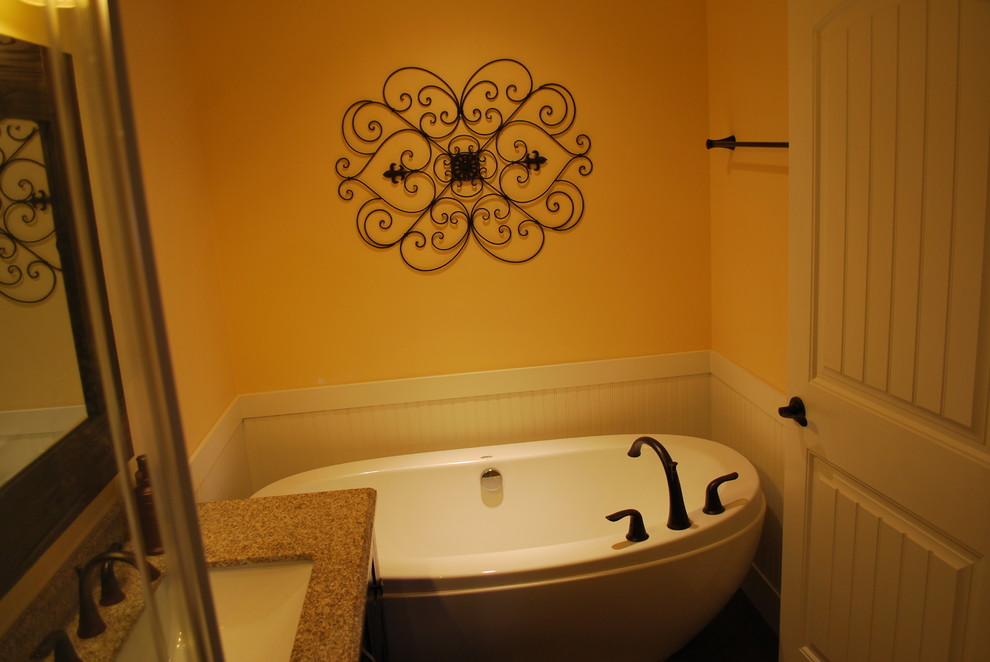 На фото: ванная комната среднего размера в стиле рустика с фасадами в стиле шейкер, темными деревянными фасадами, отдельно стоящей ванной, угловым душем, раздельным унитазом, разноцветной плиткой, каменной плиткой, желтыми стенами, темным паркетным полом, душевой кабиной, врезной раковиной, столешницей из известняка, коричневым полом и душем с раздвижными дверями