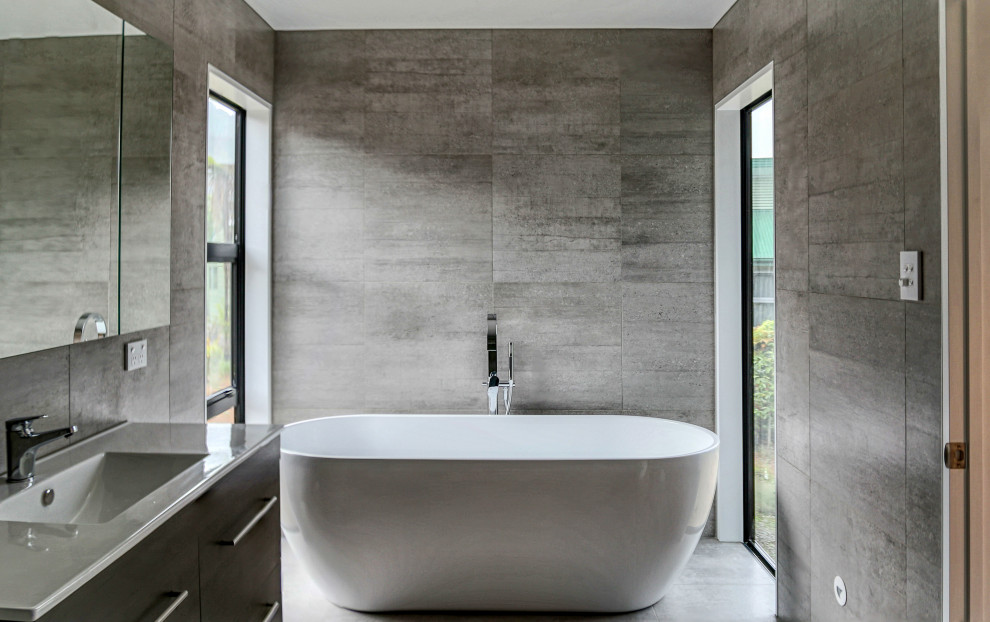 Example of a mid-sized trendy gray tile gray floor bathroom design with brown cabinets, gray walls, an integrated sink and white countertops