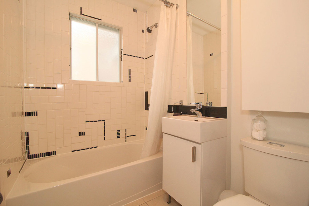 This is an example of a small world-inspired ensuite bathroom in Ottawa with an integrated sink, flat-panel cabinets, white cabinets, an alcove bath, a shower/bath combination, a one-piece toilet, white tiles, ceramic tiles, white walls and porcelain flooring.
