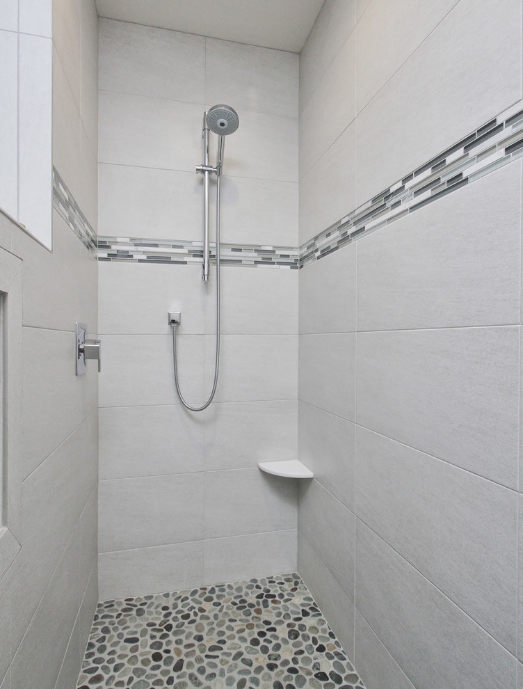 Design ideas for a medium sized ensuite bathroom in Philadelphia with flat-panel cabinets, dark wood cabinets, a freestanding bath, an alcove shower, a two-piece toilet, black and white tiles, grey tiles, multi-coloured tiles, pebble tiles, white walls, ceramic flooring, an integrated sink and solid surface worktops.