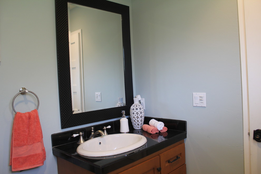Small beach style shower room bathroom in Orange County with medium wood cabinets, a one-piece toilet, grey walls, a built-in sink, solid surface worktops and black worktops.