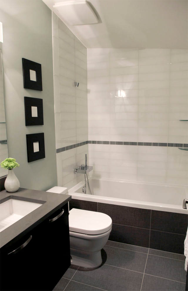 На фото: ванная комната в стиле модернизм с настольной раковиной, плоскими фасадами, темными деревянными фасадами, столешницей из искусственного кварца, накладной ванной, душем над ванной, унитазом-моноблоком, черной плиткой и плиткой из листового камня с