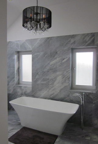 Ispirazione per una stanza da bagno contemporanea con vasca freestanding, piastrelle grigie e piastrelle in pietra