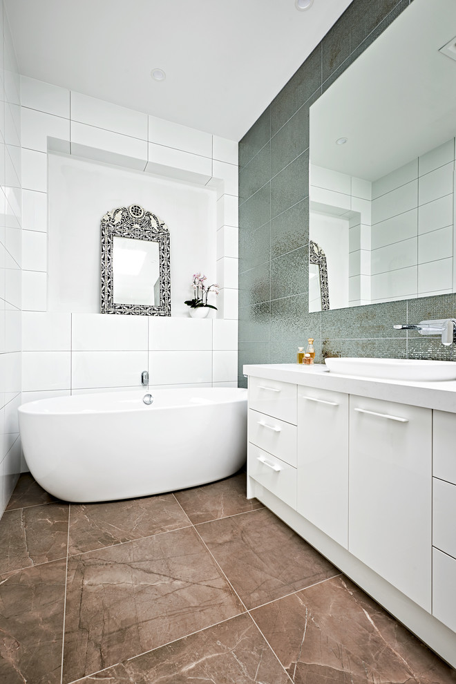 Modernes Badezimmer En Suite mit weißen Schränken, grauen Fliesen, Keramikfliesen, weißer Wandfarbe, Keramikboden, braunem Boden, weißer Waschtischplatte, flächenbündigen Schrankfronten, freistehender Badewanne und Aufsatzwaschbecken in Melbourne