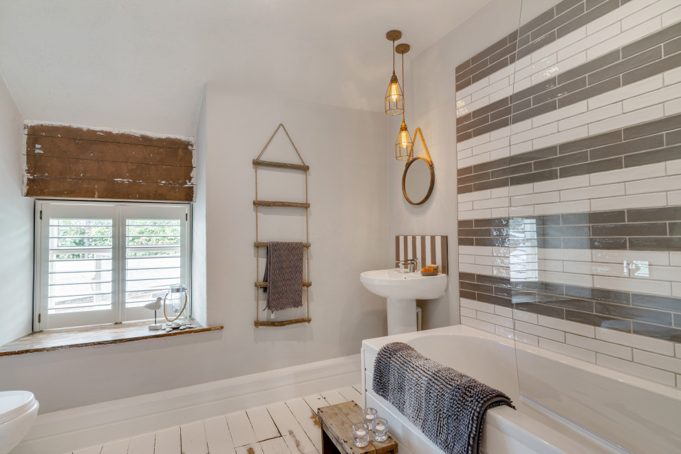 Mid-sized beach style master gray tile and terra-cotta tile painted wood floor, white floor, single-sink and shiplap wall bathroom photo in Cheshire with a wall-mount toilet, gray walls, a pedestal sink, a hinged shower door and a freestanding vanity