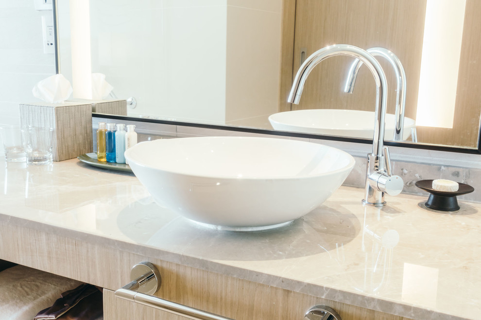 Modern inredning av ett litet badrum med dusch, med släta luckor, skåp i ljust trä, ett fristående badkar, vita väggar, klinkergolv i porslin, ett fristående handfat och marmorbänkskiva