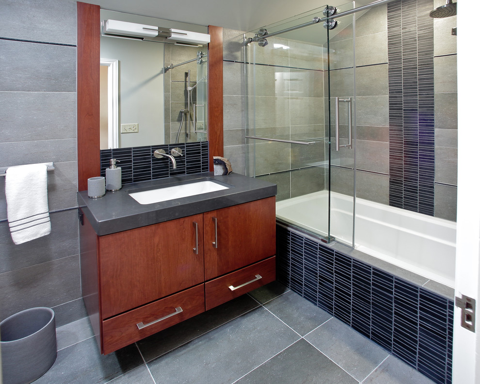 Exemple d'une salle de bain tendance en bois brun avec un lavabo encastré, un placard à porte plane, une baignoire en alcôve, un combiné douche/baignoire, un carrelage noir et des carreaux en allumettes.