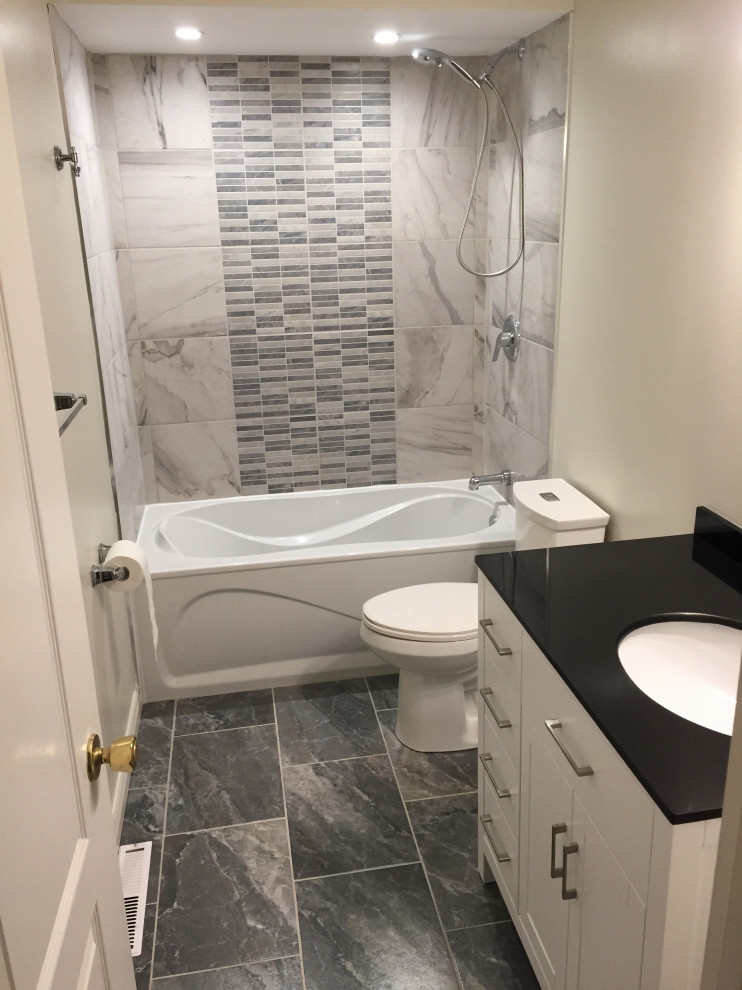 Bathroom - mid-sized traditional 3/4 gray tile and porcelain tile marble floor and black floor bathroom idea in Ottawa with shaker cabinets, white cabinets, gray walls, an undermount sink, solid surface countertops and black countertops