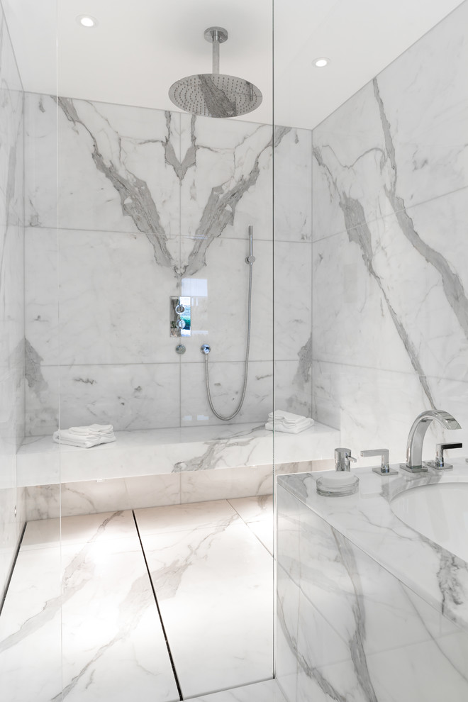 Cette photo montre une grande salle d'eau moderne avec un espace douche bain, du carrelage en marbre, un mur gris, un sol en marbre, un lavabo suspendu, un plan de toilette en marbre, un sol blanc, aucune cabine et un plan de toilette blanc.