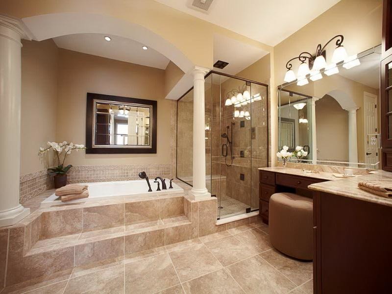 Klassisk inredning av ett stort en-suite badrum, med luckor med upphöjd panel, skåp i mörkt trä, ett platsbyggt badkar, en dusch i en alkov, en toalettstol med separat cisternkåpa, beige kakel, brun kakel, keramikplattor, beige väggar, travertin golv, ett undermonterad handfat, marmorbänkskiva, brunt golv och dusch med gångjärnsdörr