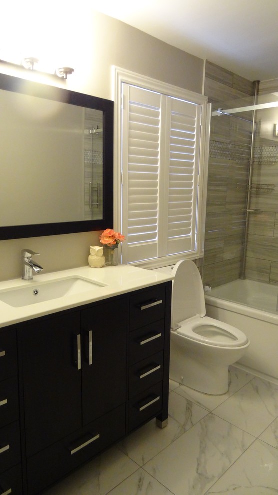 This is an example of a medium sized modern bathroom in Toronto with shaker cabinets, dark wood cabinets, a walk-in shower, a one-piece toilet, black and white tiles, porcelain tiles, grey walls, marble flooring, a built-in sink and solid surface worktops.