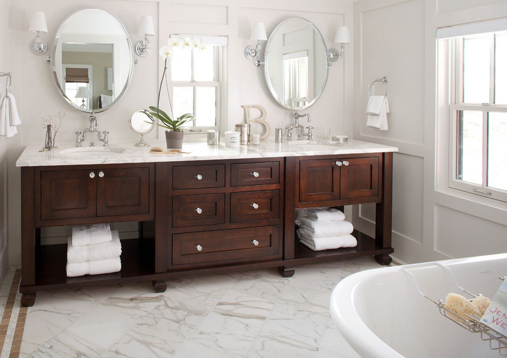 Cette image montre une salle de bain principale design en bois brun avec un lavabo encastré, un placard avec porte à panneau encastré, un plan de toilette en marbre, une baignoire indépendante et un mur blanc.